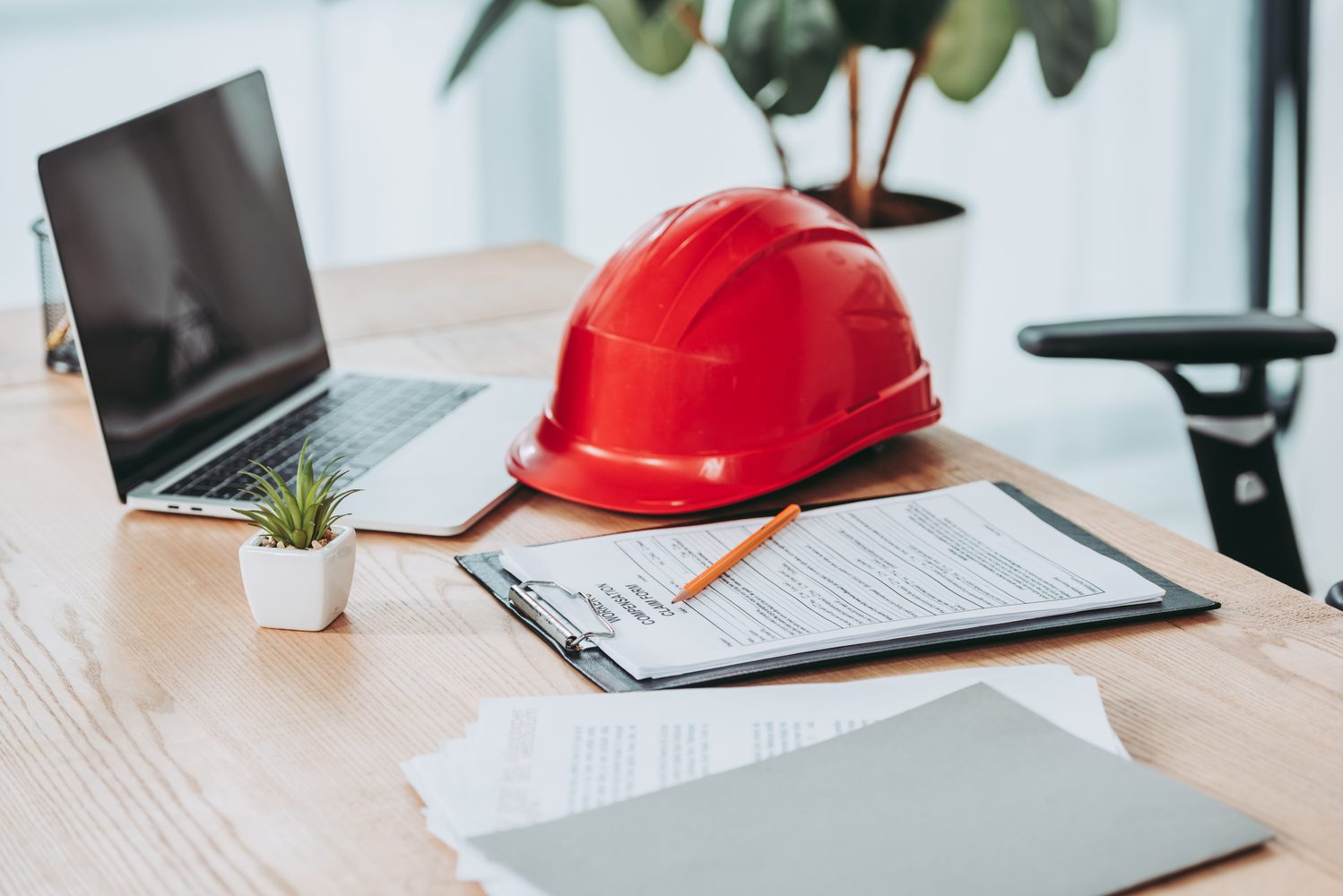 Worker compensation claim form and hard hat on a desk, representing insurance claims processing.