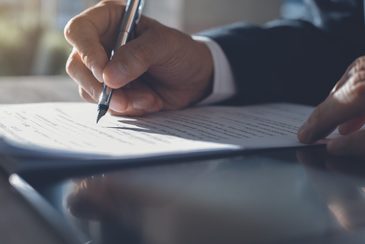 Close-up of a professional signing a contract, representing contract intelligence and compliance.